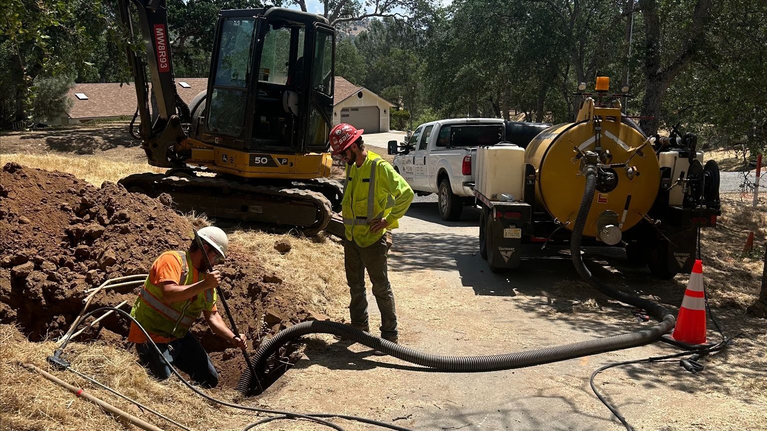 Crew using a trailer-mounted vacuum excavation unit to expose underground utilities in a trench